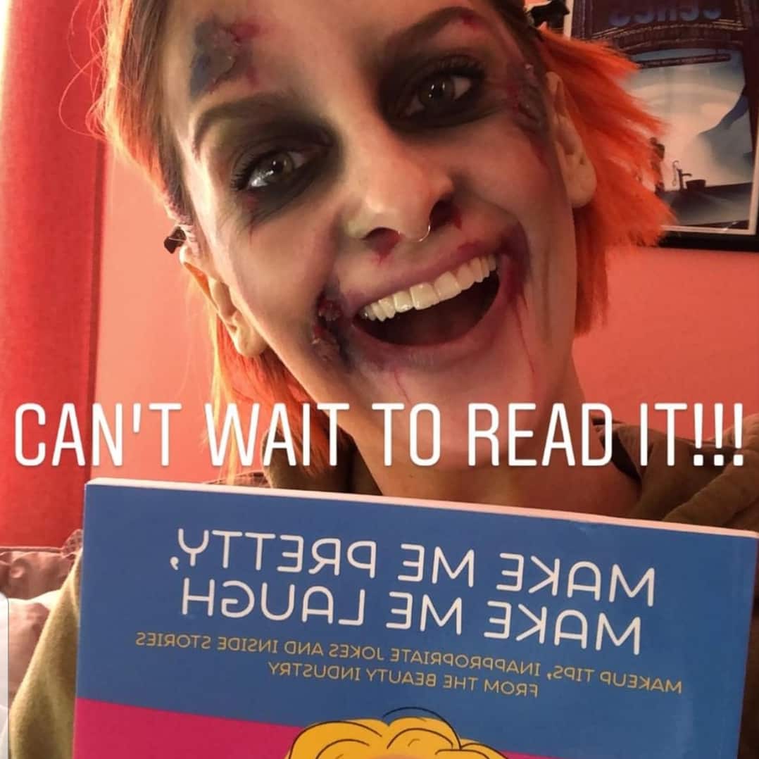 woman with scary makeup holding up a copy of Make Me Pretty, Make Me Laugh